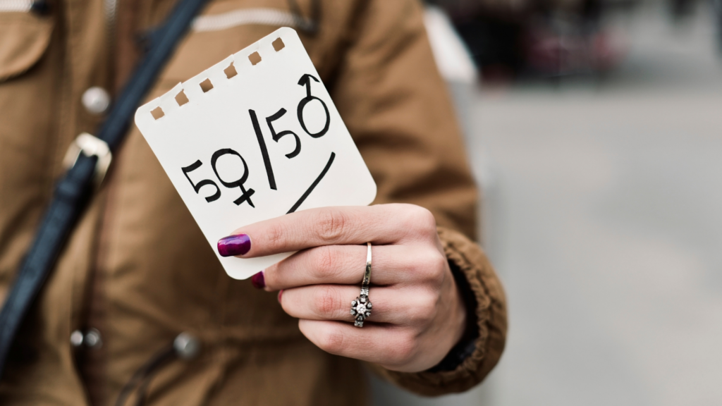 Kobieta trzymająca kartkę z napisem "50/50"